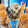 A Ben & Jerry's freshly baked dipped waffle cone with sprinkles in front of waffle cone display. A Ben & Jerry's freshly baked dipped waffle cone with sprinkles in front of waffle cone display.