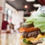 A close-up photograph of a Five Guys cheeseburger with pickles, tomatoes and jalapenos in a lettuce wrap. A close-up photograph of a Five Guys cheeseburger with pickles, tomatoes and jalapenos in a lettuce wrap.