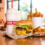 A Five Guys cheeseburger, milkshake and regular order of fries sits on a table inside a Five Guys restaurant. A Five Guys cheeseburger, milkshake and regular order of fries sits on a table inside a Five Guys restaurant.