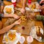 A top-down photograph of a group of friends sharing an order of fries alongside their sandwiches at a Five Guys restaurant. A top-down photograph of a group of friends sharing an order of fries alongside their sandwiches at a Five Guys restaurant.