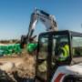 Bobcat Construction Equipment on a construction site moving pieces of material with a large machine with bucket attachment. Bobcat Construction Equipment on a construction site moving pieces of material with a large machine with bucket attachment.