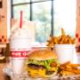 A Five Guys cheeseburger, milkshake and regular order of fries sits on a table inside a Five Guys restaurant. A Five Guys cheeseburger, milkshake and regular order of fries sits on a table inside a Five Guys restaurant.