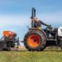 Man driving a Bobcat Compact Tractor looking backward at three-point hitch Man driving a Bobcat Compact Tractor looking backward at three-point hitch