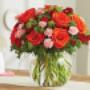 A vibrant bouquet of orange roses, red carnations, pink mini carnations, and lush greenery beautifully arranged in a round glass vase. The floral centerpiece is ideal for fall celebrations, romantic occasions, or as a stunning Thanksgiving decoration. A vibrant bouquet of orange roses, red carnations, pink mini carnations, and lush greenery beautifully arranged in a round glass vase. The floral centerpiece is ideal for fall celebrations, romantic occasions, or as a stunning Thanksgiving decoration.